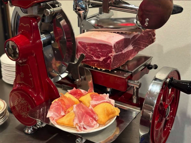 Chef carving prosciutto by hand at Prosciutto, East Village NYC